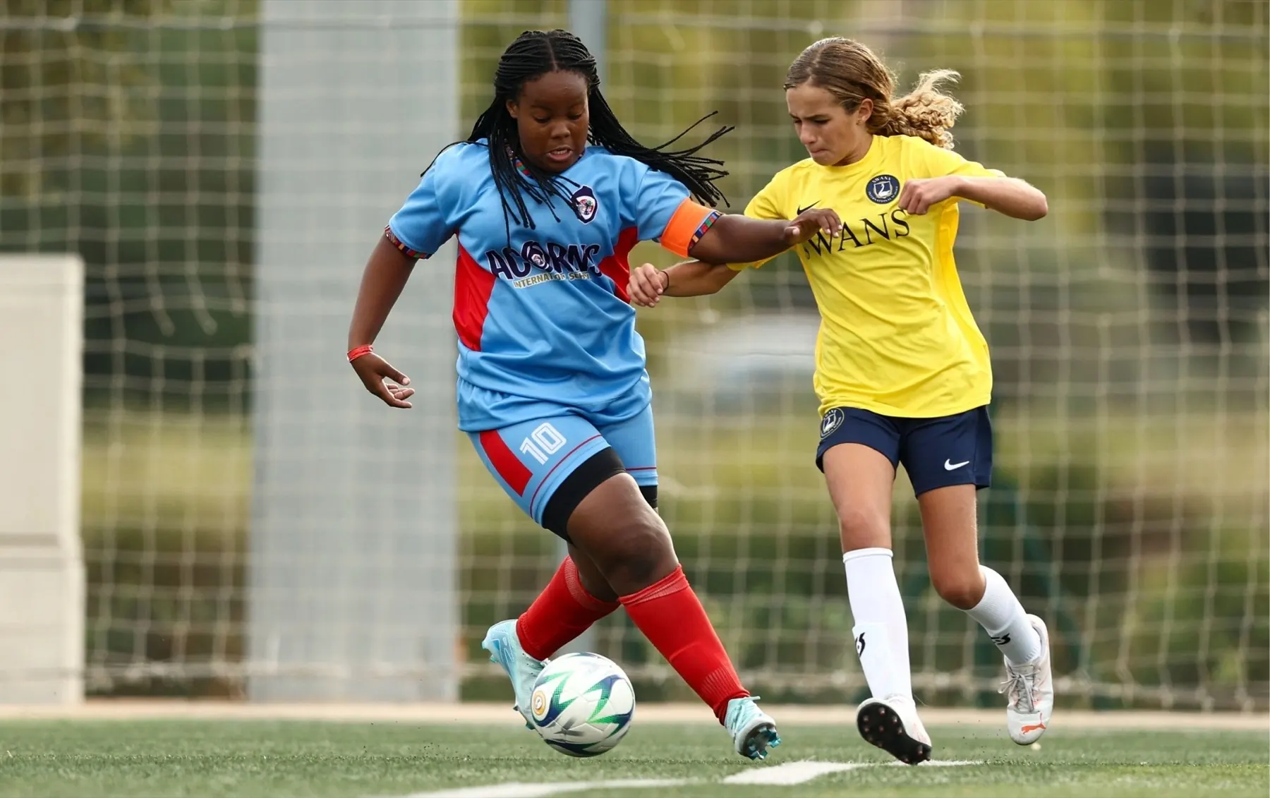 Two girls racing for the ball