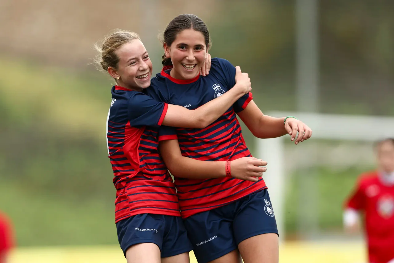 Two teammates hugging and laughing after a goal