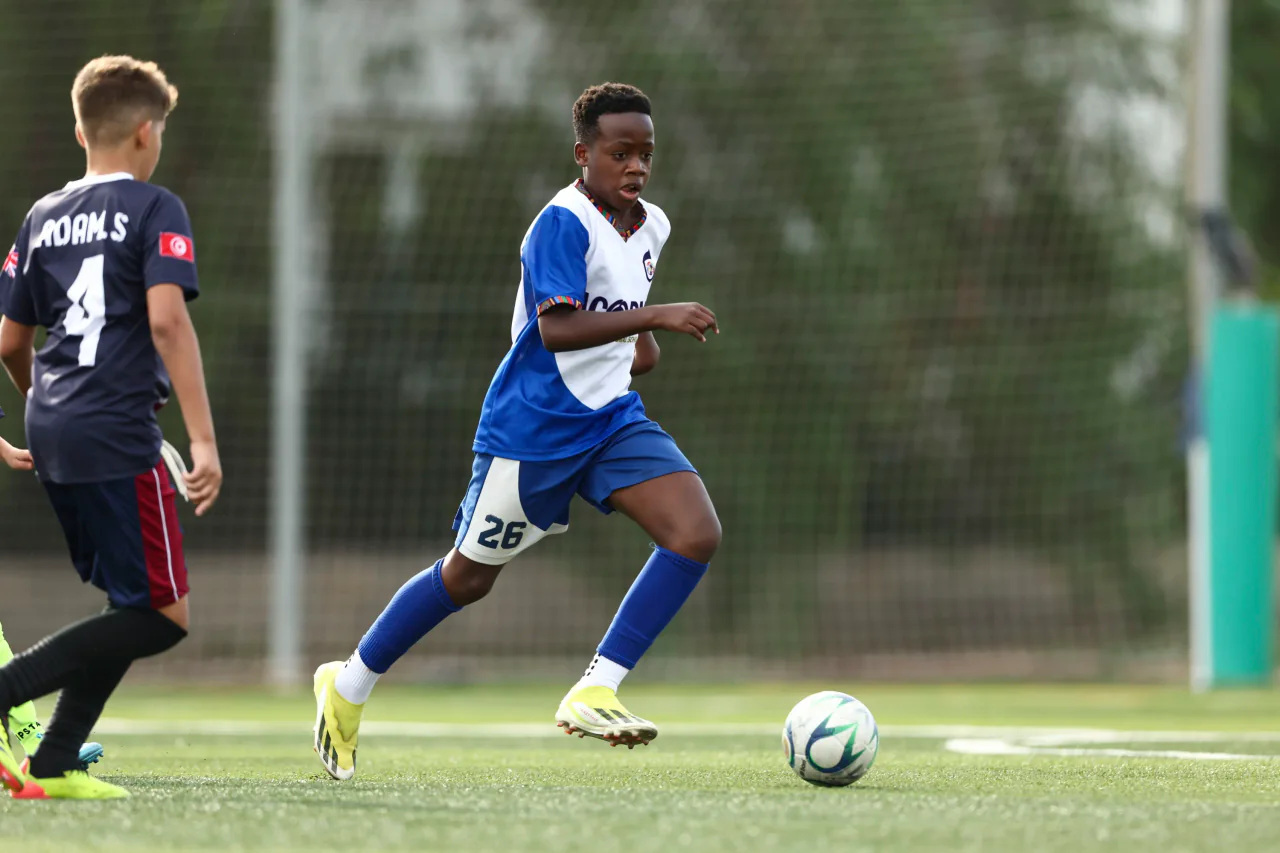 A young player, number 26, running onto the ball